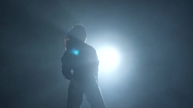 Modern koreografi yaratıcı konsept. Stüdyoda dans eden bir kadının silueti. Siyah arka plan dumanla dolu, beyaz spot ışıkları arkadan parlıyor. Yavaş çekim.