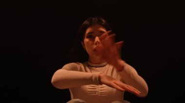 Modern koreografi yaratıcı konsept. Kadın dansçı, yerdeki bir stüdyoda caz funk 'ın enerjik koreografisini yapıyor. Sıcak sarı spot ışıkları altında koyu bir arka plan. Yavaş çekim.