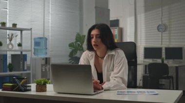 Yaratıcı iş konsepti. Genç iş kadını yönetici ofiste masa başında oturuyor belgelerle uğraşıyor, işini bitiriyor bilgisayarı kapatıp odada dans etmeye başlıyor..