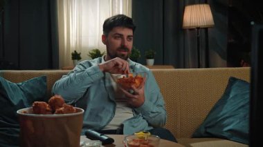 Abur cubur reklamı konsepti. Sakallı adam evde fast food dağıtımı ile vakit geçiriyor, kanepede oturup televizyon izliyor ve bir kaseden patates cipsi yiyor. Yavaş çekim