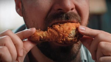 Abur cubur reklamı konsepti. Sakallı adamın, elinde tuttuğu ve tavuk budu çiğneyip ısırdığı, fast food 'un tadını çıkardığı yakın çekim. Yavaş çekim