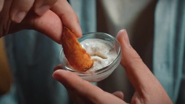 Abur cubur reklamı konsepti. Sakallı adamın yakın plan fotoğrafı, sosa batırılmış patates tutan ve çiğneyen, fast food yemekten hoşlanan adam. Yavaş çekim