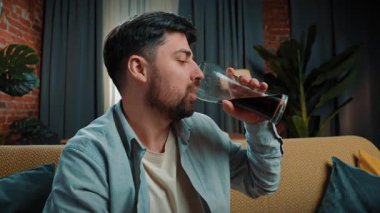 Abur cubur reklamı konsepti. Sakallı adam evde fast food dağıtımıyla vakit geçiriyor, kanepeye oturuyor ve büyük bir bardaktan kola içiyor, bir yudum alıyor ve tadını çıkarıyor. Yavaş çekim