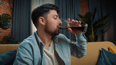 Abur cubur reklamı konsepti. Sakallı adam evde fast food dağıtımıyla vakit geçiriyor, kanepeye oturuyor ve büyük bir bardaktan kola içiyor, bir yudum alıyor ve tadını çıkarıyor. Yavaş çekim