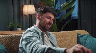 Abur cubur reklamı konsepti. Sakallı adam evde fast food dağıtımı ile vakit geçiriyor, kanepede oturup televizyonda komik filmler izliyor, gülümsüyor ve soslu kızarmış tavuk yiyor..