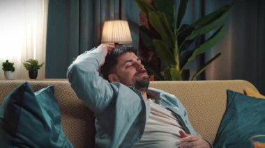 Abur cubur reklamı konsepti. Sakallı adam evde fast food dağıtımı yapıyor, kanepeye oturuyor ve televizyon seyrediyor, uykulu esniyor ve uykuya dalıyor..