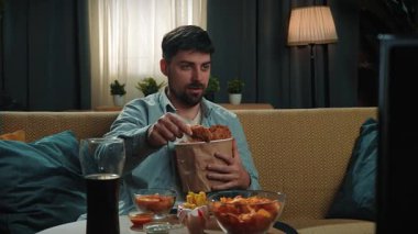 Abur cubur reklamı konsepti. Sakallı adam evde fast food dağıtımı ile vakit geçiriyor, kanepede oturup spor televizyon izliyor, ekranla konuşuyor ve soslu tavuk yiyor. Yavaş çekim