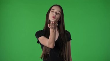Gençlik duyguları konsepti. Genç kız göz kırparak poz veriyor ve hava öpücüğü veriyor, olumlu ifade, krom anahtar yeşil ekran arka plan modelinde izole edilmiş..