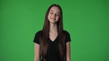 Gençlik duyguları konsepti. Kameraya gülümseyen ve başını sallayan genç kız, pozitif ifade, krom anahtar yeşil ekranda izole edilmiş arka plan modeli..