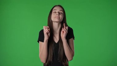 Gençlik duyguları konsepti. Çapraz parmaklı ve endişeli yüzlü genç kız mutluluk patlamaları, olumlu kazanan yüz ifadesi, krom anahtar yeşil ekran arka plan modelinde izole.