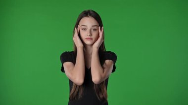 Gençlik duyguları konsepti. Kameraya poz veren genç kız baş ağrısı ve masaj tapınakları, yorgun yüz ifadesi, krom anahtar yeşil ekran arka plan modelinde izole edilmiş..
