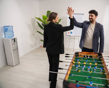 Ofisteki langırt molası sırasında iş arkadaşları beşlik çakıyor, takım çalışmasını ve coşkuyu teşvik ediyor..