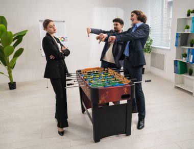 Modern ofis ortamında bir mola sırasında üç meslektaşım canlı bir langırt maçına katılıyor..