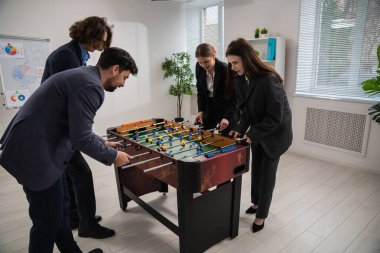 Modern ofis ortamında rekabetçi bir langırt maçının keyfini çıkaran bir grup meslektaş, takım çalışmasını ve rahatlamayı teşvik ediyor..