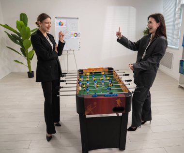 Takım elbiseli iki meslektaş modern bir ofiste eğlenceli bir langırt oyununun keyfini çıkarıyorlar, takım çalışmasını ve arkadaşlığı teşvik ediyorlar..