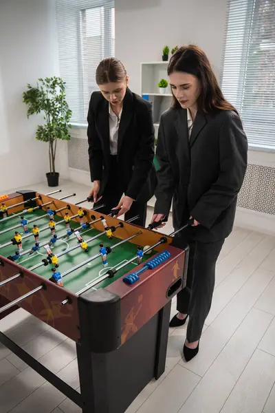 İş dünyasından iki kadın modern bir ofis ortamında langırt oyununda hevesle yarışıyor..