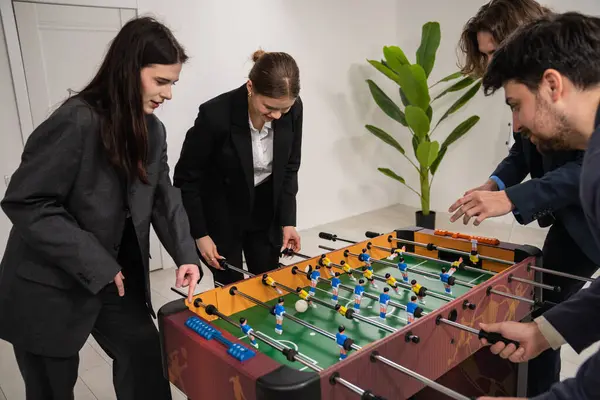 Dört meslektaş yoğun bir şekilde ofis ortamında langırt oynuyor, takım çalışması ve dostluk sergiliyorlar..