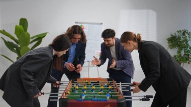 Bir grup iş arkadaşı modern ofis ortamında futbol oynayıp takım çalışmasını ve eğlencesini destekliyor..