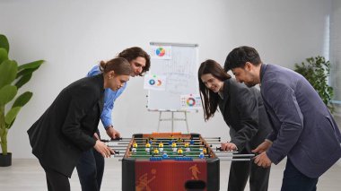 Ofis ortamında langırt oynayan bir grup meslektaş, takım çalışmasını ve arkadaşlığı vurguladı.