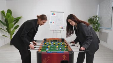 İki iş kadını modern ofis ortamında takım ruhunu geliştiren rekabetçi bir langırt oyunu oynuyorlar..