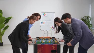 Dört meslektaş modern ofis ortamında langırt oynamayı, takım çalışmasını ve rahatlamayı teşvik etmeyi seviyorlar..