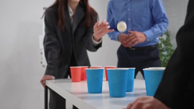 Ofis çalışanları renkli fincanlar kullanarak eğlenceli bir bira pong oyunu oynarlar. Takım oluşturma aktivitesi, arkadaşlığı teşvik ediyor. Kapat.
