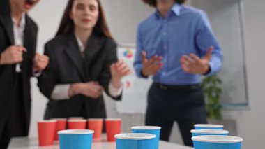Ofisteki meslektaşlar bardaklarla etkileşimli bir oyun oynuyorlar, eğlenceli ve canlı bir atmosfer yaratıyorlar..