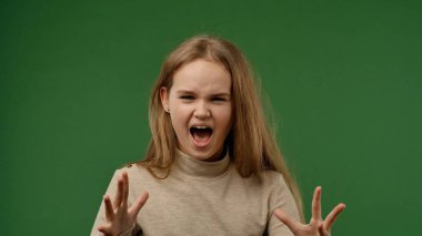Gençlik duyguları konsepti. Genç kız kameraya poz veriyor ve bağırıyor sinirli bir yüz ifadesiyle, olumsuz bir ifadeyle, krom anahtar yeşil ekran arka plan modelinde izole edilmiş..