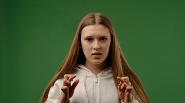 Gençlik duyguları konsepti. Genç kız kameraya poz veriyor ve endişeli bir yüz, pozitif bir ifade bekliyor. Krom anahtar yeşil ekran arka plan modelinde izole edilmiş..