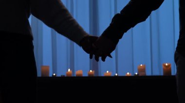 Romantik bir sahne, bir çiftin el ele tutuşup, mum ışığında durduğu bir sahne. Yavaş çekim.