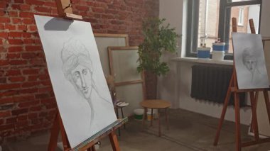 Sanatsal beceriler geliştirmek için eğitim boş zamanı aktivitesi. Resim odası, kadın kalem portreli tuval resim sehpaları ve antika kadın kafa modeli heykeli. Yavaş çekim.