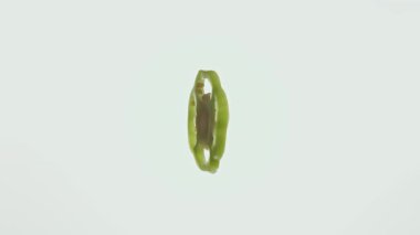 Hafif bir arka plana yerleştirilmiş canlı yeşil dolma biber dilimi doğal şeklini vurguluyor..