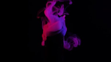 Peri mor dumanının canlı bir görüntüsü koyu siyah bir arkaplanda zarafetle kıvrılarak gizem ve zarafet hissi yaratıyor. Yavaş çekim