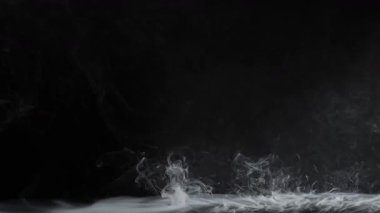 Pürüzsüz bir sıvı yüzeyden gizemli bir atmosfer yaratarak karanlık bir arkaplana doğru yükselen ruhani dumanlar. Yavaş çekim