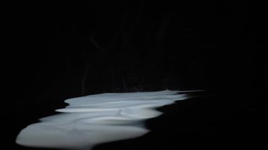 Pürüzsüz bir sıvı yüzeyden gizemli bir atmosfer yaratarak karanlık bir arkaplana doğru yükselen ruhani dumanlar. Yavaş çekim