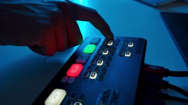 Erkekler kayıt konsolundaki tuşları elle değiştirirler. Çeşitli monitörleri, kameraları ve kontrolleri olan profesyonel video yapım stüdyosu canlı yayın ve çekim için kullanılıyor. Yavaş çekim.