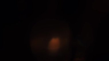 Karanlık bir ortamda parlayan ışık yansımaları ve bokeh efektlerinin soyut bir bileşimi gizemli ve atmosferik bir hava yaratıyor. Yavaş çekim.