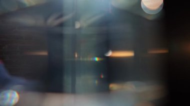 Karanlık bir ortamda parlayan ışık yansımaları ve bokeh efektlerinin soyut bir bileşimi gizemli ve atmosferik bir hava yaratıyor. Yavaş çekim.