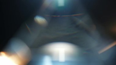 Karanlık bir ortamda parlayan ışık yansımaları ve bokeh efektlerinin soyut bir bileşimi gizemli ve atmosferik bir hava yaratıyor. Yavaş çekim.