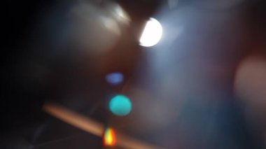 Karanlık bir ortamda parlayan ışık yansımaları ve bokeh efektlerinin soyut bir bileşimi gizemli ve atmosferik bir hava yaratıyor. Yavaş çekim.