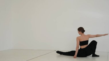 Siyah elbiseli genç kadın beyaz arka planda çağdaş dans ediyor..