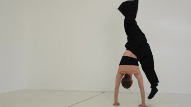 Siyah elbiseli genç kadın beyaz arka planda çağdaş dans ediyor..