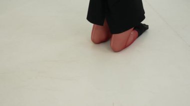 Siyah elbiseli genç kadın beyaz arka planda çağdaş dans ediyor..