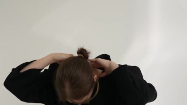 Siyah elbiseli genç kadın beyaz arka planda çağdaş dans ediyor..