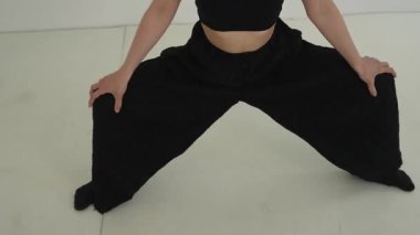 Siyah elbiseli genç kadın beyaz arka planda çağdaş dans ediyor..