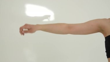 Siyah elbiseli genç kadın beyaz arka planda çağdaş dans ediyor..