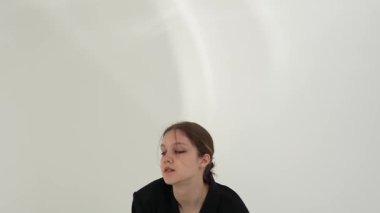 Siyah elbiseli genç kadın beyaz arka planda çağdaş dans ediyor..