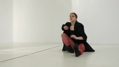 Siyah elbiseli genç kadın beyaz arka planda çağdaş dans ediyor..