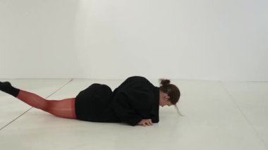 Siyah elbiseli genç kadın beyaz arka planda çağdaş dans ediyor..