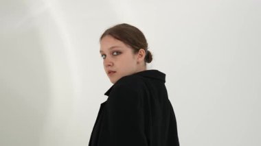 Siyah elbiseli genç kadın beyaz arka planda çağdaş dans ediyor..